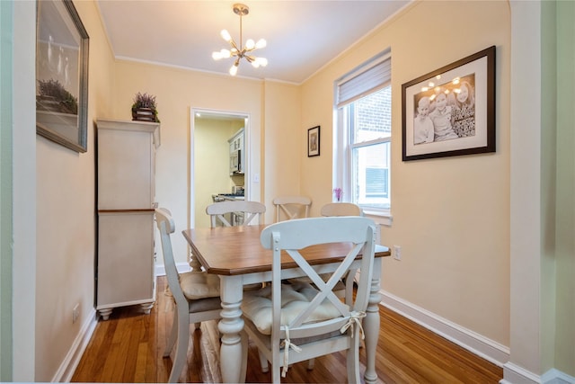 dining area with a notable chandelier, dark wood-type flooring, and ornamental molding