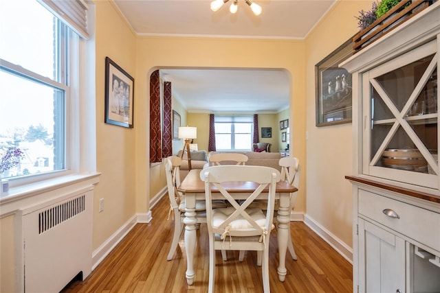 dining area with radiator, crown molding, and light hardwood / wood-style floors