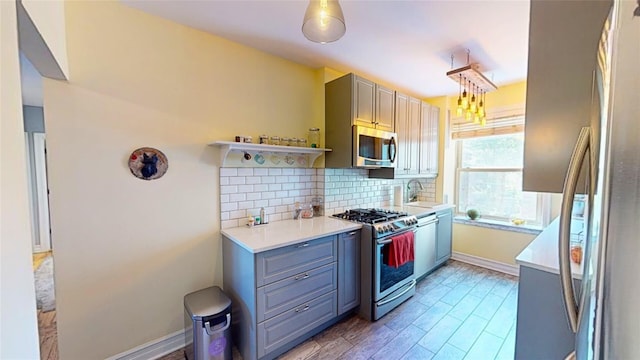 kitchen with sink, gray cabinets, stainless steel appliances, hardwood / wood-style floors, and backsplash