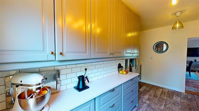 kitchen with tasteful backsplash, light stone countertops, dark wood-type flooring, and pendant lighting