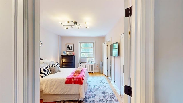 bedroom with radiator heating unit and light wood-type flooring