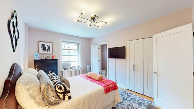 bedroom with a closet, radiator heating unit, and light hardwood / wood-style flooring