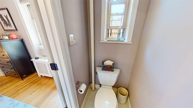 bathroom with toilet, radiator, and hardwood / wood-style floors