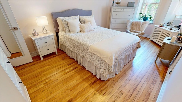 bedroom with radiator and light hardwood / wood-style floors