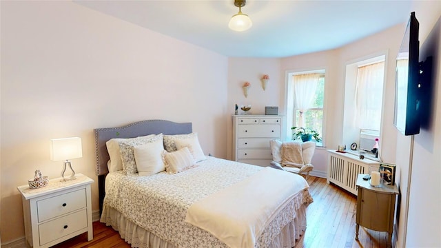 bedroom featuring radiator heating unit and light hardwood / wood-style flooring