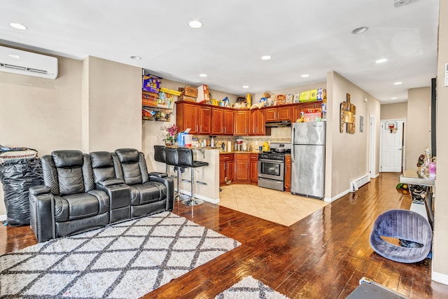 living room featuring a baseboard radiator, a wall mounted air conditioner, and light hardwood / wood-style floors