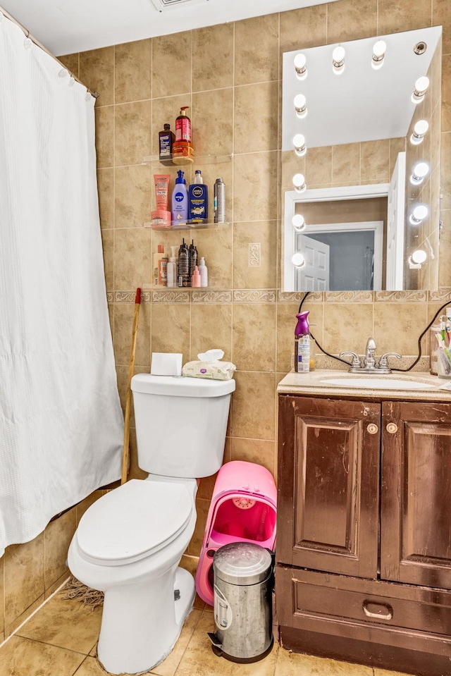 bathroom with toilet, tile patterned flooring, and tile walls