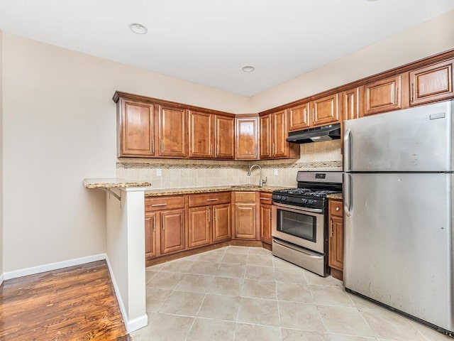 kitchen featuring light stone counters, sink, decorative backsplash, and stainless steel appliances