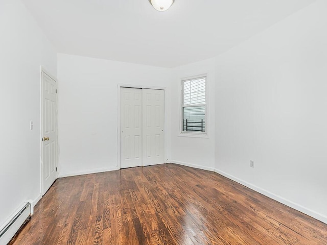 unfurnished bedroom with dark wood-type flooring, a baseboard radiator, and a closet