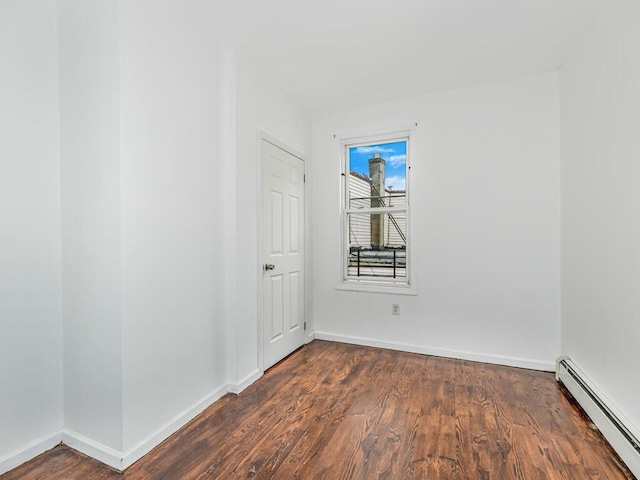 spare room with a baseboard radiator and dark hardwood / wood-style flooring