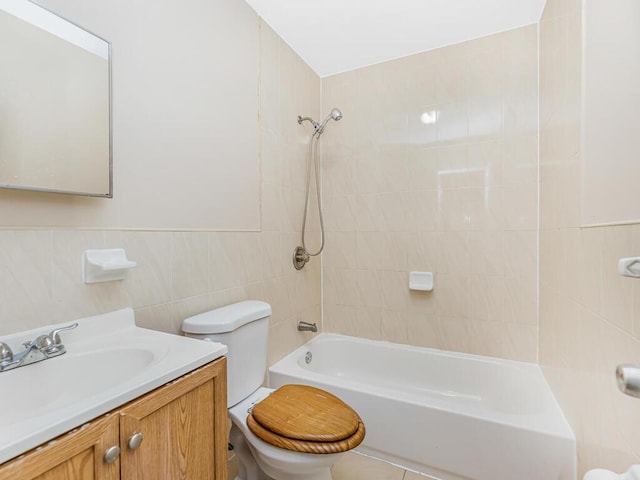 full bathroom featuring vanity, toilet, tiled shower / bath combo, and tile walls