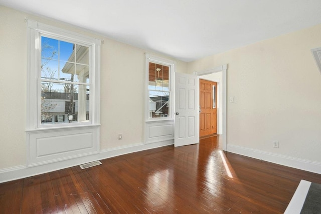 empty room featuring plenty of natural light and dark hardwood / wood-style flooring