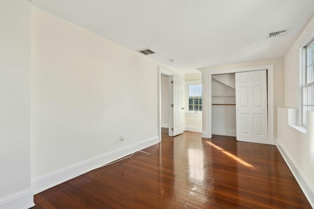 unfurnished bedroom with dark hardwood / wood-style flooring and a closet