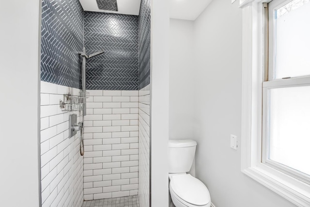 bathroom featuring a tile shower and toilet