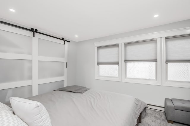 carpeted bedroom featuring a baseboard radiator and a barn door