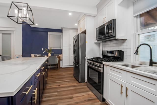 kitchen featuring pendant lighting, sink, dark wood-type flooring, appliances with stainless steel finishes, and white cabinets