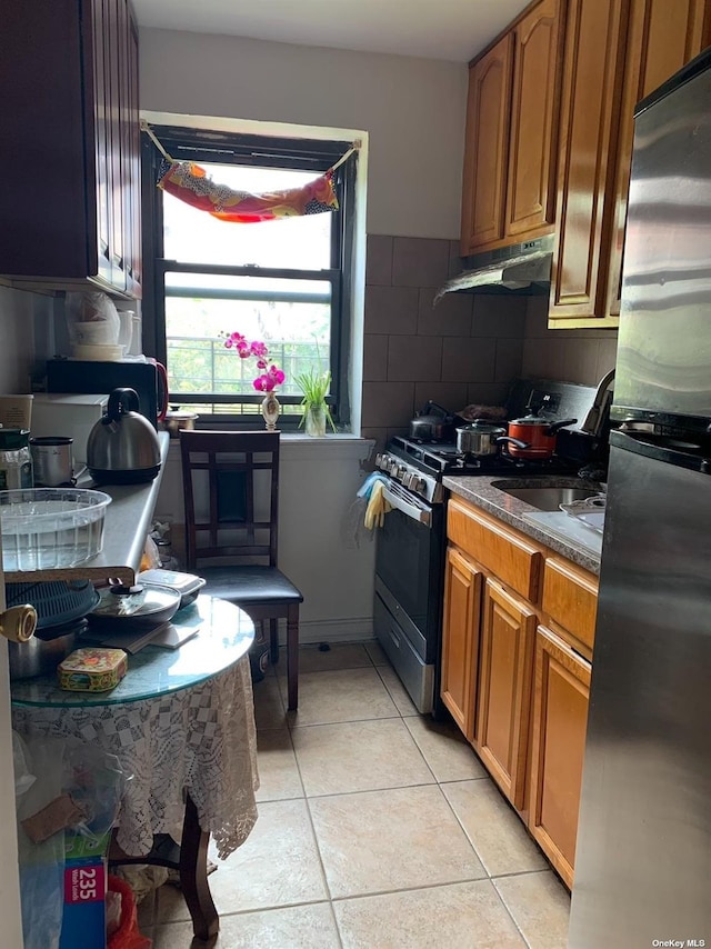 kitchen with light tile patterned flooring, appliances with stainless steel finishes, sink, and decorative backsplash