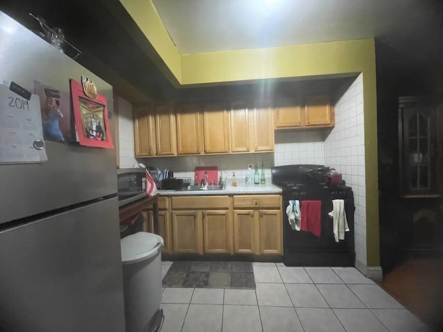 kitchen featuring light tile patterned flooring, appliances with stainless steel finishes, sink, and decorative backsplash