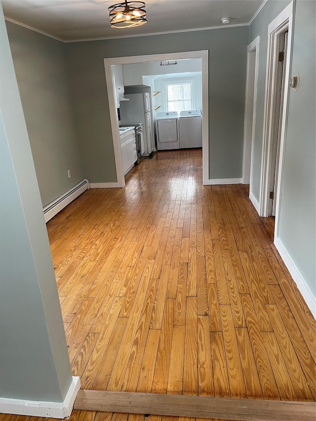 interior space featuring crown molding, a baseboard heating unit, washing machine and clothes dryer, and light hardwood / wood-style flooring