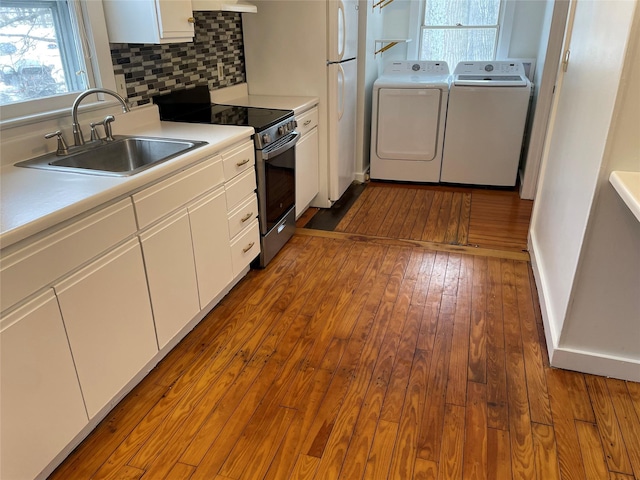 kitchen with stainless steel electric range oven, hardwood / wood-style floors, white cabinetry, sink, and washing machine and clothes dryer