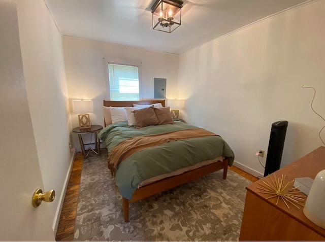 bedroom with dark wood-type flooring, ornamental molding, and electric panel