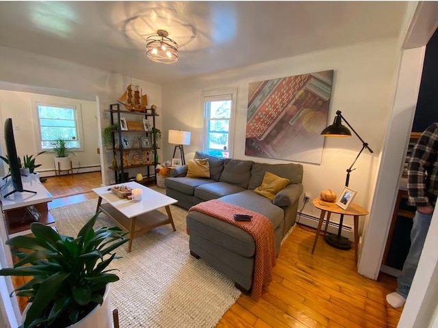 living room with a baseboard heating unit, a wealth of natural light, and light wood-type flooring