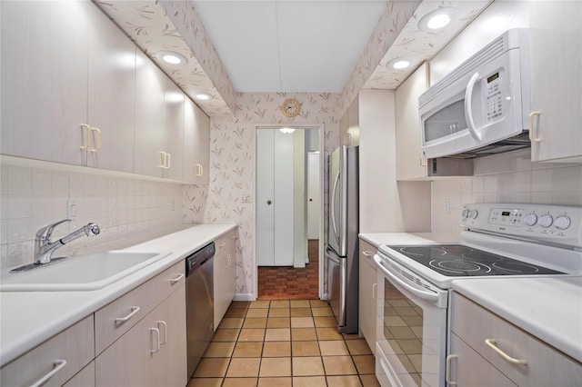 kitchen featuring stainless steel appliances, sink, light tile patterned floors, and decorative backsplash