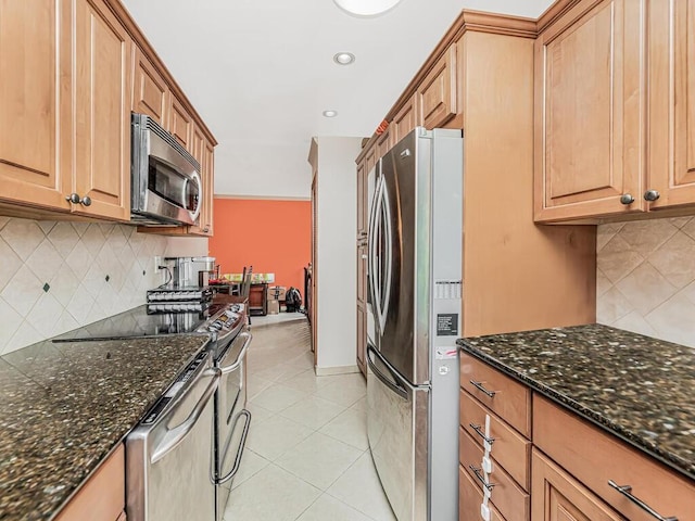 kitchen featuring dark stone countertops, light tile patterned floors, decorative backsplash, and appliances with stainless steel finishes