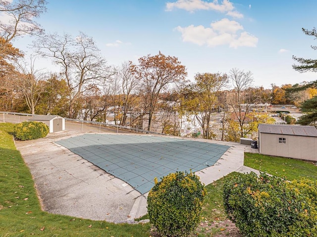 view of pool with a storage unit, a patio area, and a lawn