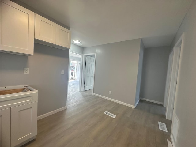 kitchen with hardwood / wood-style flooring, white cabinetry, and sink