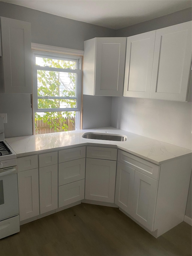 kitchen featuring sink, dark wood-type flooring, white gas stove, and white cabinets