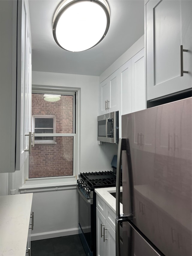 kitchen with white cabinetry, stainless steel appliances, and light stone countertops