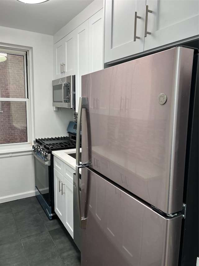 kitchen featuring dark tile patterned floors, white cabinetry, and appliances with stainless steel finishes