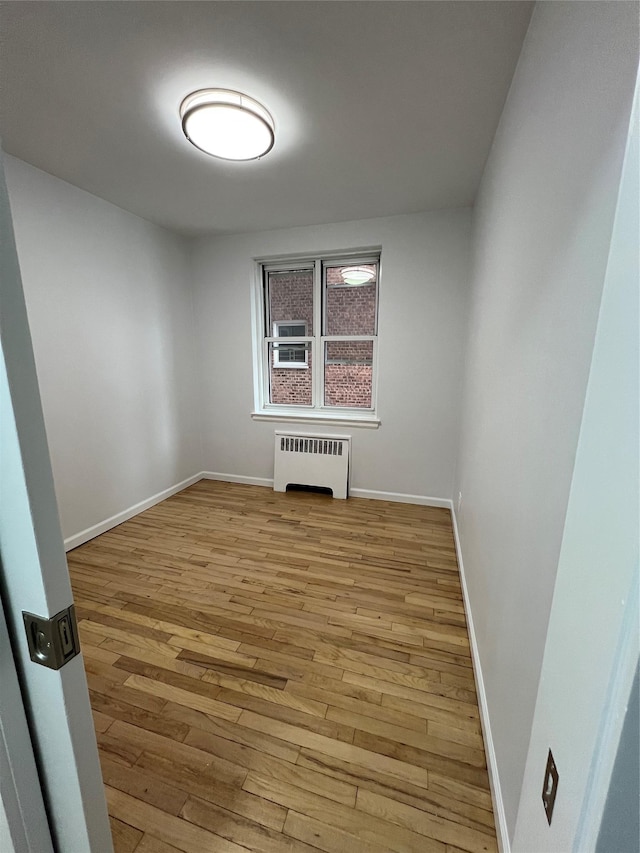 empty room featuring radiator heating unit and light hardwood / wood-style flooring