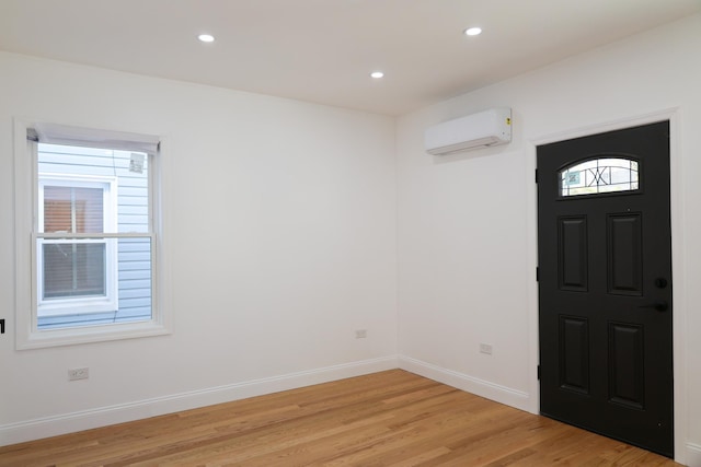 foyer entrance featuring plenty of natural light, light wood-type flooring, and an AC wall unit