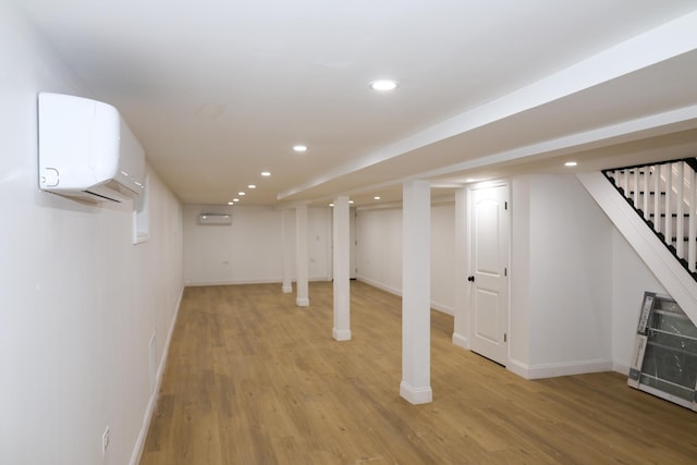 basement with a wall mounted AC and light wood-type flooring