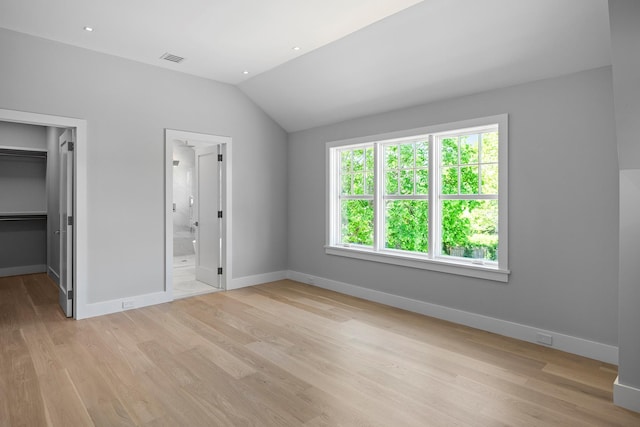 245 Mill Rd, Westhampton Beach, NY 11978 - unfurnished bedroom with a spacious closet, vaulted ceiling, light wood-type flooring, and baseboards