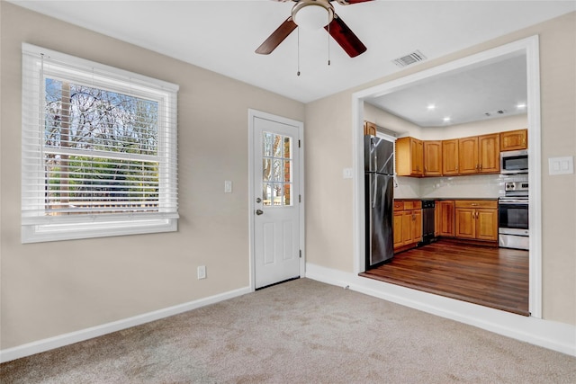 kitchen with appliances with stainless steel finishes, light carpet, and ceiling fan