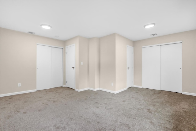 unfurnished bedroom featuring multiple closets and carpet flooring