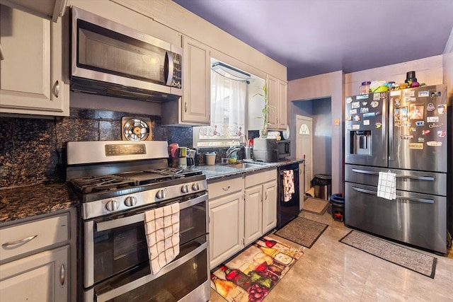 kitchen with dark stone countertops, sink, backsplash, and appliances with stainless steel finishes