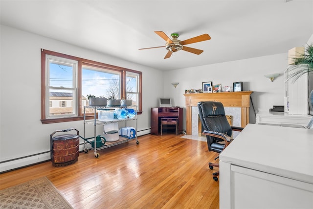 home office featuring light wood-style floors, a baseboard heating unit, ceiling fan, and baseboard heating