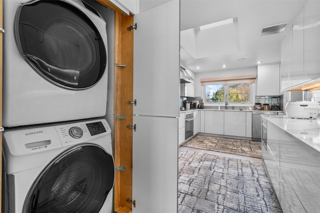 laundry room with laundry area, visible vents, stacked washer / drying machine, and recessed lighting