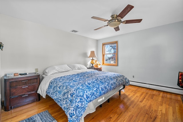 bedroom featuring a baseboard radiator, visible vents, ceiling fan, and wood finished floors