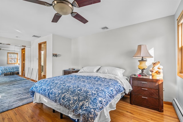 bedroom featuring attic access, visible vents, baseboard heating, and wood finished floors