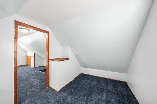 bonus room with vaulted ceiling and dark colored carpet