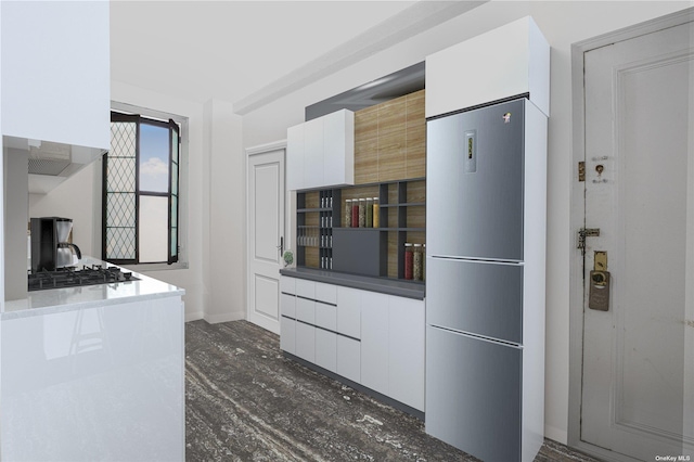 kitchen featuring gas stovetop, white cabinets, and refrigerator