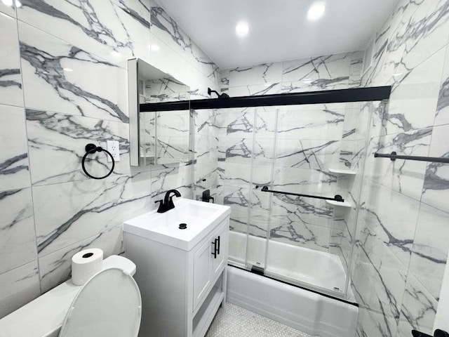 bathroom with toilet, shower / bath combination with glass door, vanity, and tile walls