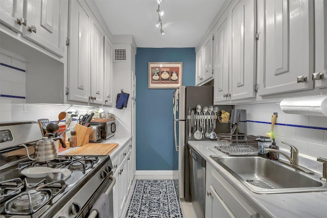 kitchen with sink, light tile patterned floors, appliances with stainless steel finishes, white cabinets, and decorative backsplash