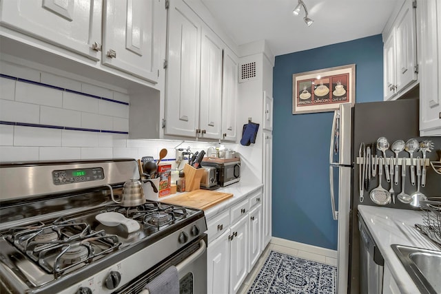 kitchen with white cabinets, tile patterned floors, stainless steel appliances, and tasteful backsplash