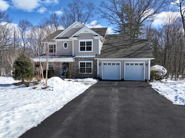 view of front of home featuring a garage, stone siding, and aphalt driveway